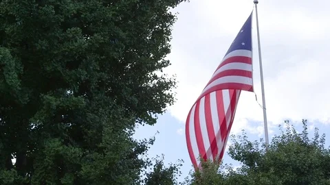 Large American Flag Flying Under Bright Blue Cloudy Sky Vídeo Stock 80039046