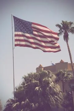 Large American flag mounted on a pole with a walled building on the horizon Fotos de archivo
