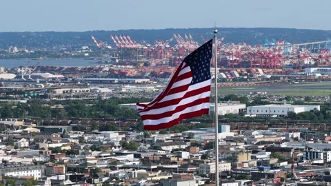 Large American flag waves above dense city rooftops in Newark, New Jersey Stock Footage 340971082