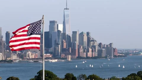 Large American flag waves proudly before Lower Manhattan skyline, One World Stock Footage 340969996