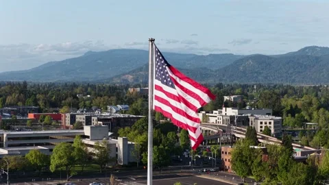 Large American flag waving dramatically on tall flagpole above Eugene downtown Stockbeeldmateriaal 336687057