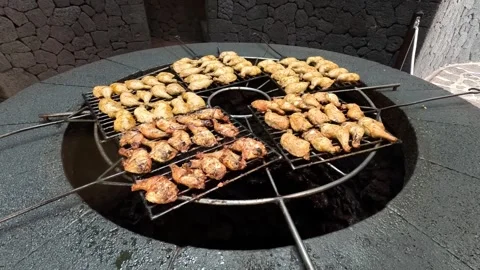 Large amount of chicken legs on large volcano heated grill 4k Stock Footage 276409207