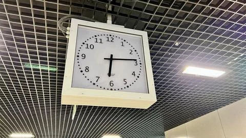 Large analog clock hanging from the ceiling at a station Foto stock
