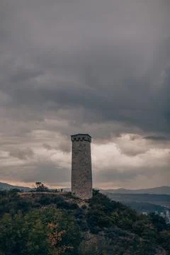 Large ancient stone tower stands on a hill in the forest. Stock Photos