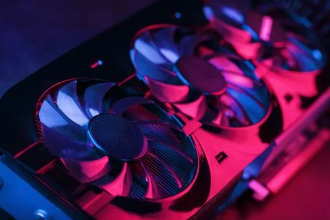Large and powerful graphics card with three fans with blue pink light. Stock Photos