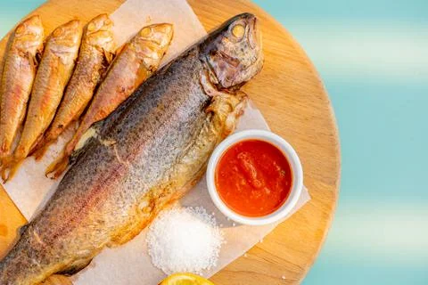 Large and small fried fish on a wooden board, Sauce, salt. close-up. Stock Photos