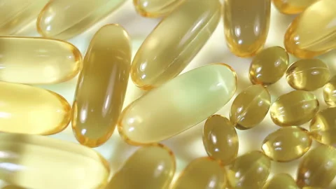 Large and small oval light yellow capsules of fat-soluble vitamins. Non-contrast Stock Footage 145107949