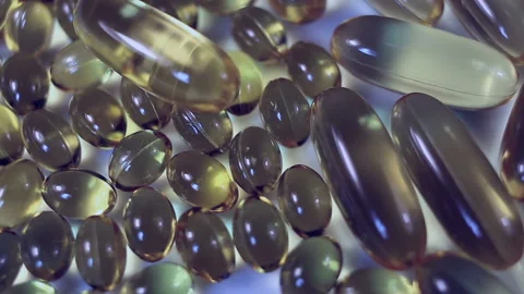 Large and small oval transparent yellow capsules on a purple background move fro Stock Footage 145107605