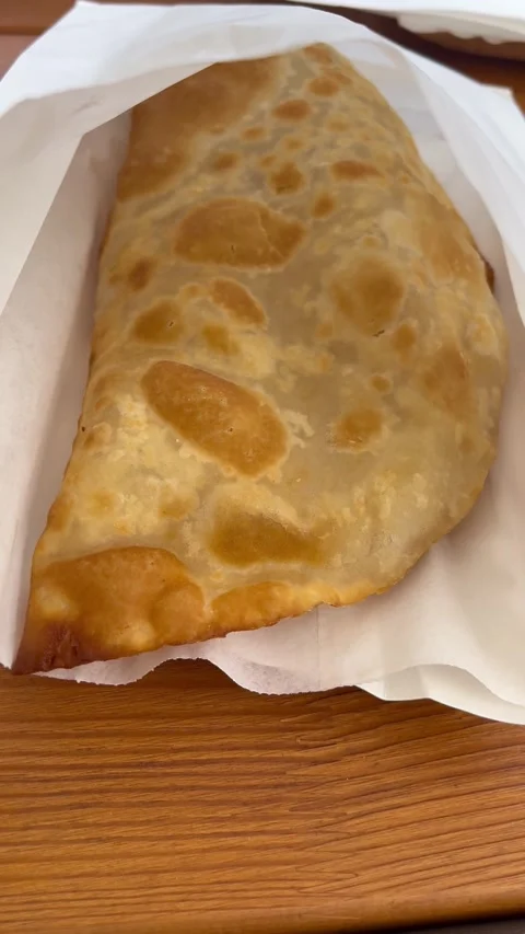 A large appetizing hot cheburek lies in a white paper bag on the table. Stock Footage 282774159