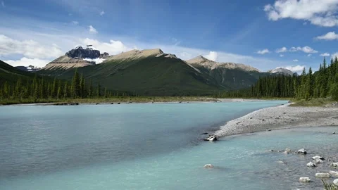 A large aqua green colored river flows out of a beautiful panoramic mountain set Stock Footage 142241256