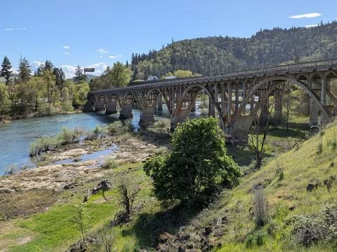 Large arched concrete bridge spanning a wide river with low water levels Foto stock