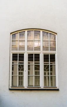A large arched window with white framed panes reflects interior curtains an.. Stock Photos