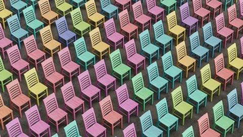 A Large Array of Colorfully Stained Wooden Chairs Facing a Single Direction Stock Illustration
