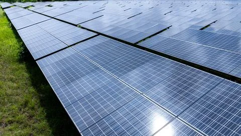 Large Array Of Photovoltaic Solar Panels Set In A Green Field During A Sunn.. Stock Photos