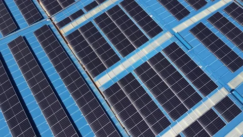 Large array of solar panels mounted on a bright blue industrial rooftop Vídeo Stock 345103221