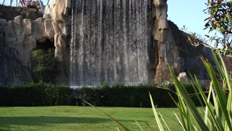 Large artificial waterfall cascading down rocky cliff Stock Footage 321006189