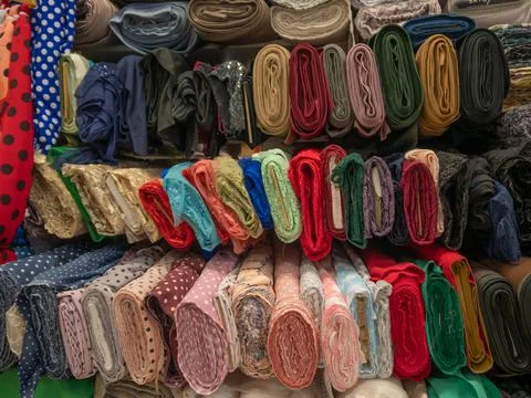 A large assortment of different fabrics in the store. Samples of colored natu Stock Photos