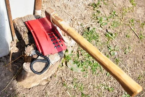 A large ax sticks out in an outdated push-button telephone. Stock Photos