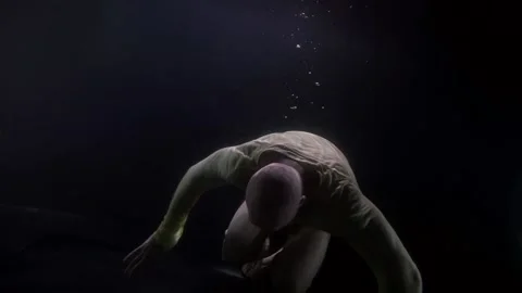A large bald man swims in the dark under the water head first Видео 165931729