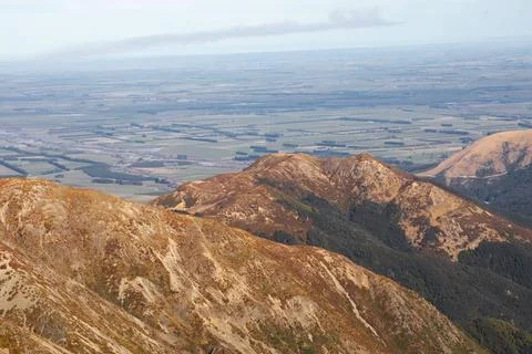 Large bare mountain range against green valley under sky Stock Photos