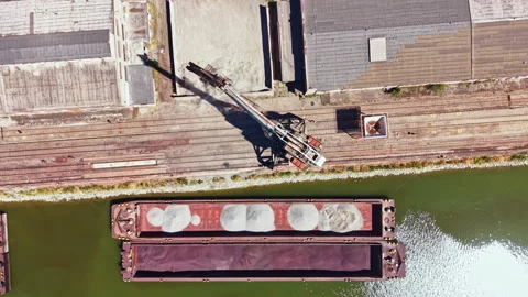 Large barge unloading sand by crane at a commercial dock on a river in the Stock Footage 344087586