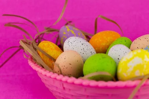 Large basket of colorful Easter eggs on a pink background. Preparation for the Stock Photos