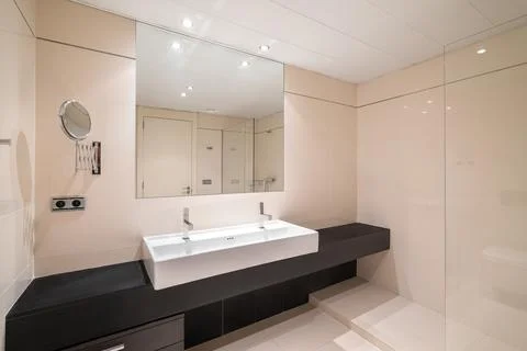 Large bathroom with two ceramic white washbasins on massive black marble Photos