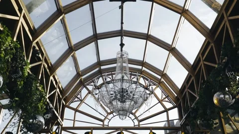 A large, beautiful chandelier hangs under the transparent glass ceiling Stock Footage 302111594