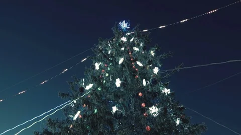 A large, beautiful Christmas tree is decorated with ornaments and garlands. 스톡 동영상 81744825