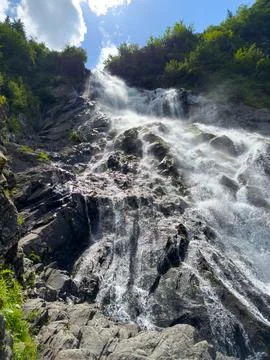 A large beautiful waterfall flows down from the mountains Stock Photos