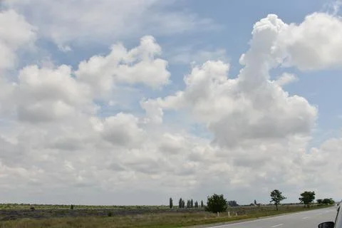 A large beautiful white cloud hangs low over a green field during the day Stock Photos