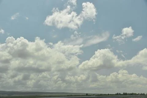 A large beautiful white cloud hangs low over a green field during the day Stock Photos