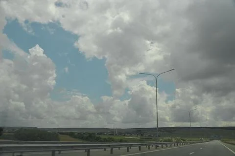 A large beautiful white cloud hangs low over a green field during the day Stock Photos