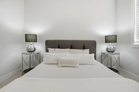 Large bed with two lamps on either side of it Stock Photos