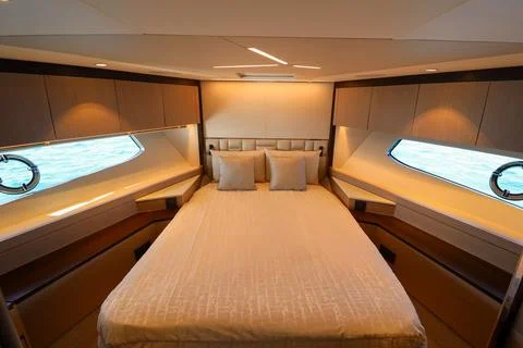 A large bed with a white comforter and pillows in luxury boat Stock Photos