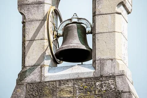 A large bell hangs from a stone tower. Stock Photos