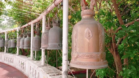 Large bells hanging in a row of Golden Mount temple hang in open area near Stock Footage 303684302