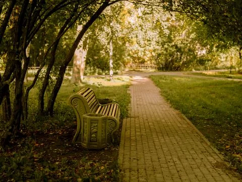 Large bench on the path in the Park among the trees, autumn background, road Stock Photos