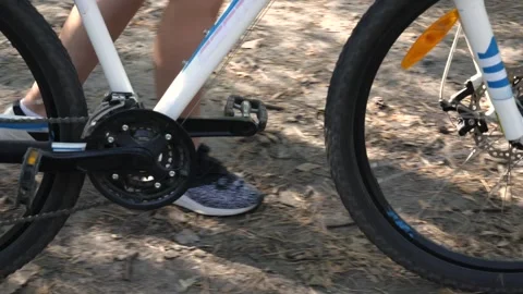 Large bicycle wheels that guide along a dirt road, close-up of a girl's legs. Vídeos de archivo 250564663