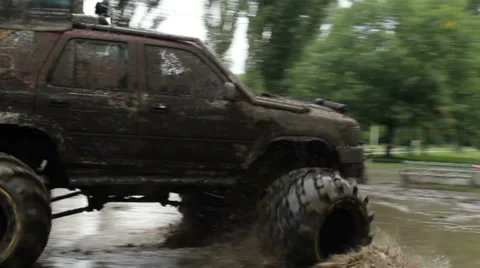 Large bigfoot car completely in dirt turns around mud puddle, click for HD Stock Footage