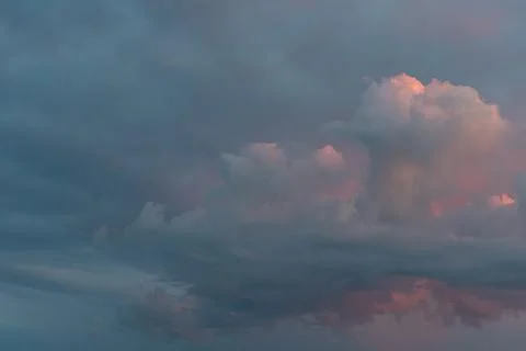 Large, billowing cloud with soft pink and orange hues dominates a serene sky  Stock Photos