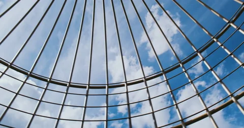 Large bird cage, camera looking up and moving around. Blue sky with clouds, sun Stock Footage