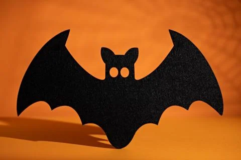 Large black bat silhouette centered on orange background for Halloween part.. Stock Photos