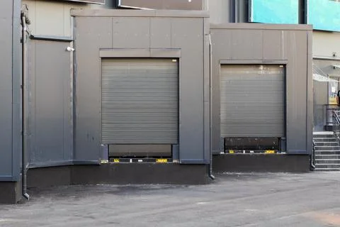 A large black building featuring a loading dock along with stairs Stock Photos