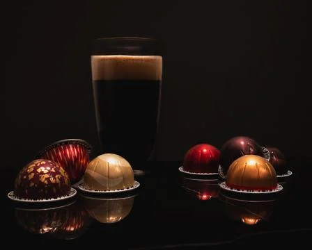 Large black coffee in a double wall glass cup with foam, colourful coffee pods Stock Photos