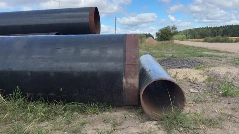 Large black metal pipes lying on ground at rural construction site  Vídeo Stock 343409932