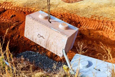 Large block being lowered into construction site near red clay ground Fotos Stock
