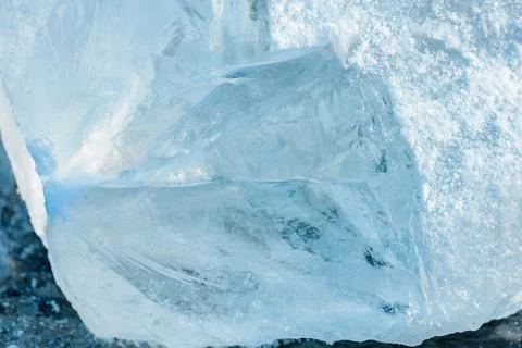 Large block of clear ice with intricate patterns and textures, resting on a.. Stock Photos