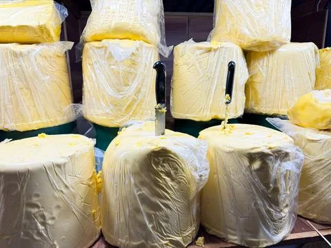 Large blocks of butter wrapped in plastic packet with knives inserted, displayed Stock Photos