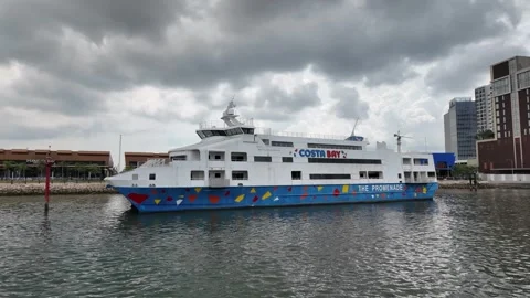 A large blue and white ferry boat Costa Bay is floating in the water near a dock Видео 318270218